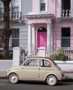 Beige colour vintage Fiat 500 classic car parked in front of a house with a pink door on a street in Notting Hill, Londond UK Royalty Free Stock Photo