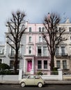 Beige colour vintage Fiat 500 classic car parked in front of a house with a pink door on a street in Notting Hill, Londond UK Royalty Free Stock Photo