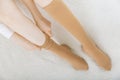 Beige compression stockings on a woman in a white room. Knee socks or socks. Girl putting on stockings at home Royalty Free Stock Photo