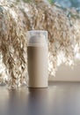 Beige cosmetic bottle against a background of reed flowers. Beauty concept Royalty Free Stock Photo
