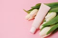 Beige cosmetic tube with cream or lotion for body and bouquet of white tulips on beige background Royalty Free Stock Photo