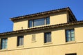 Beige or creame colored stucco cement building with gray roof tiles and exterior facade in downtown city with windows Royalty Free Stock Photo