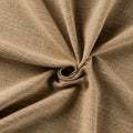 Beige fabric with a textured surface is gathered into a swirl pattern. It has visible threa Royalty Free Stock Photo