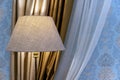 Beige floor lamp on a background of golden curtains and white tulle