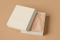 A beige gift box with a partially open lid, revealing crumpled tissue paper inside. Royalty Free Stock Photo