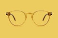 Beige and golden plastic color eye glasses isolated on yelloww background, ideal photo template for display or advertising sign or Royalty Free Stock Photo