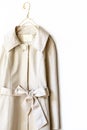 Beige or greige elegant trench coat with ribbon over white