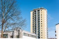 Beige high rise apartment building towering over lower buildings