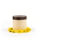 Beige jar with brown lid, mocap for cream, balm, mask and small yellow daisies on a white background.