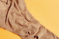 Beige knitted fabric on yellow paper. Autumn shades of pastel tones