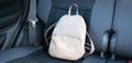 Beige leather backpack on a grey backseat of a car