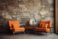 Beige lounge chair near orange loveseat sofa against wood and stone paneling wall. Mid-century style home interior design Royalty Free Stock Photo