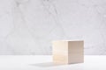 Beige natural cube podium in white and grey marble interior with sun light and shadow. Showcase for cosmetic products, goods.