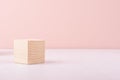 Beige natural wood podium of cube shape on white wood table and pastel pink wall. Showcase for cosmetic products, packings. Royalty Free Stock Photo