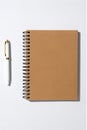 beige notepad with a spiral mount and a white pen on a white background