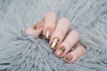 beige Nude manicure with gold lace pattern on a gray background