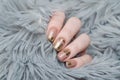 beige Nude manicure with gold lace pattern on a gray background