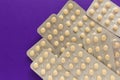 Beige pills inside medicine box. Purple background. Royalty Free Stock Photo