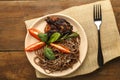 Beige plate soba with chicken tomatoes and spinach on a linen napkin on the table.