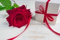 Beige polka dot gift box with red ribbon bow and bautiful red roses on wooden background. Greeting card for holiday Royalty Free Stock Photo