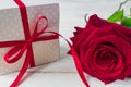 Beige polka dot gift box with red ribbon bow and bautiful red roses on wooden background. Greeting card for holiday Royalty Free Stock Photo