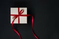Beige polka dot gift box with red ribbon bow on black background with copy space. Top view Royalty Free Stock Photo