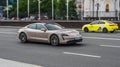 Beige Porsche Taycan in motion. Speeding in city road concept. All-electric premium car, front side view Royalty Free Stock Photo