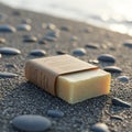 Beige rectangular soap with a brown paper wrapper featuring text is placed on a pebbl Royalty Free Stock Photo