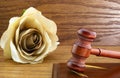 Beige rose with brown gavel on wood background