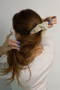 Beige scrunchie on blond long hair scattered in motion of making ponytail. View from the back. White background. Caucasian woman Royalty Free Stock Photo