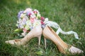 Beige shoes of the bride with a bright bouquet and a ring stand on the green grass. The concept of love and marriage Royalty Free Stock Photo