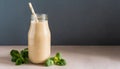 Beige smoothie in glass bottle with paper straw on table. Tasty drink Royalty Free Stock Photo