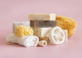 Beige soap bars, seashells, natural sponges and towel on light pink close up