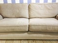 Beige sofa near the wall with striped wallpaper