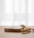 A beige stone slab on a wooden tabletop in front of a window with dried flowers