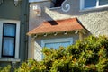 Beige stucco home exterior with adobe red small roof tiles and green house next door with front yard trees and hidden Royalty Free Stock Photo