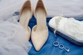 Beige suede female shoes, clutch bag and golden wedding rings on blue background, copy space. Royalty Free Stock Photo