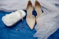 Beige suede female shoes, clutch bag and golden wedding rings on blue background, copy space. Royalty Free Stock Photo