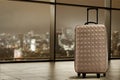 Suitcase on tiled floor in apartment with large window with night cityscape background. Royalty Free Stock Photo