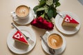 on the beige table there are two pairs of coffee with cakes with hearts and a bouquet Royalty Free Stock Photo