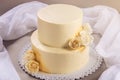 Beige 2 tiered wedding cake decorated with mastic roses stands on fabric background Royalty Free Stock Photo