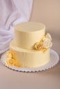 Beige 2 tiered wedding cake decorated with mastic roses stands on fabric background Royalty Free Stock Photo