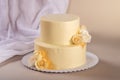 Beige 2 tiered wedding cake decorated with mastic roses stands on fabric background Royalty Free Stock Photo