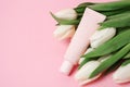 Beige tube with cosmetic cream or lotion for body and bouquet of white tulips, pink background, copy space Royalty Free Stock Photo