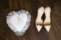 Beige wedding bridal shoes and gold wedding rings on white decorate pillow