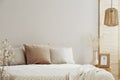 Beige and white pillows on comfortable bed, copy space on empty wall Royalty Free Stock Photo