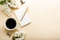 Beige and white work space with coffee cup, notepad and lilac flowers Royalty Free Stock Photo