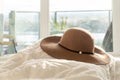 Beige woman`s round sun hat with floral trim and wide brim, on a fluffy comforter in a bedroom, with balcony in the background. Royalty Free Stock Photo