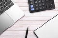 Beige wooden desk table with pen, notepad, calculator and Macbook. Apple Inc. is an American multinational technology company.