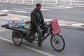 Man rides on freight tricycle in street scene.